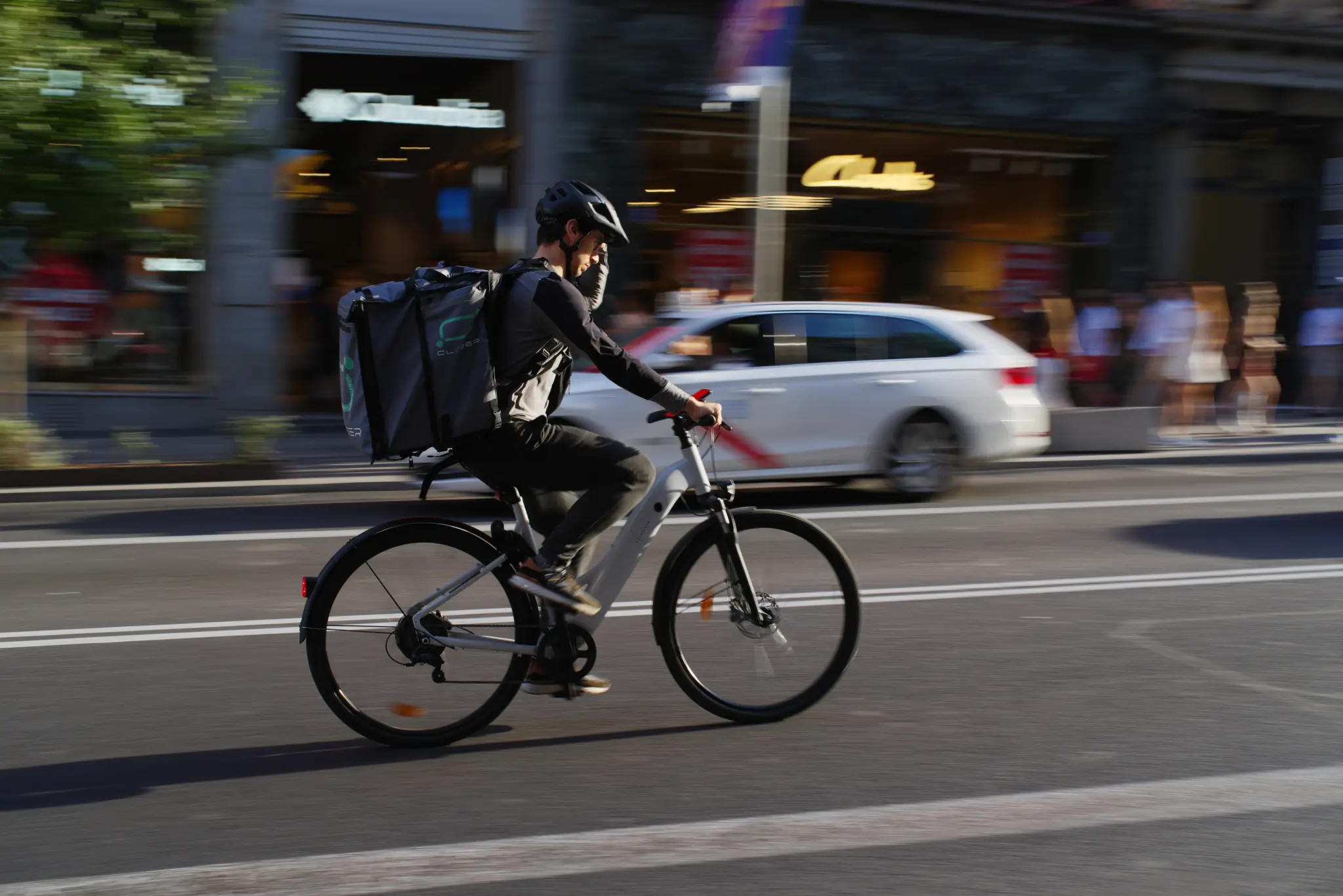 Coursier à vélo avec un sac de livraison roulant dans une avenue urbaine