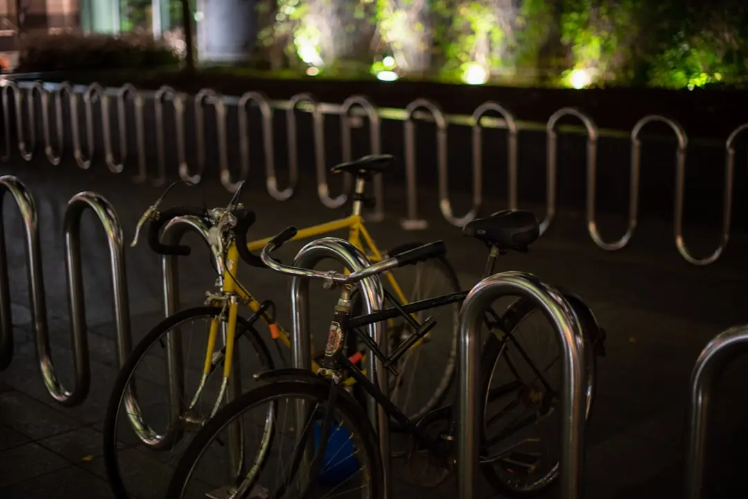 black bicycle leaning on gray metal fence during daytime