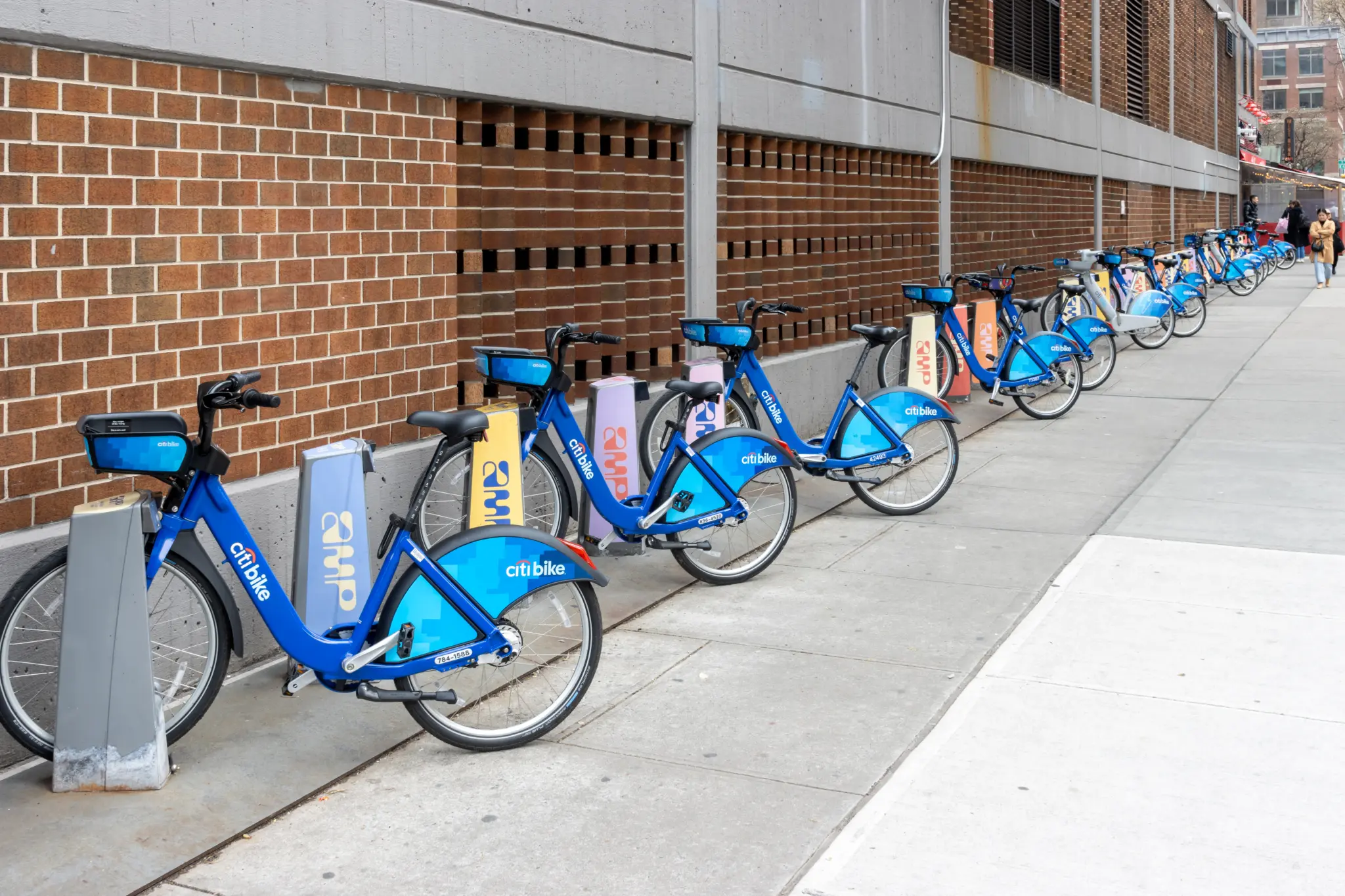 Une rangée de vélos Citi Bike, dont des modèles à assistance électrique, garés le long d'un trottoir à New York