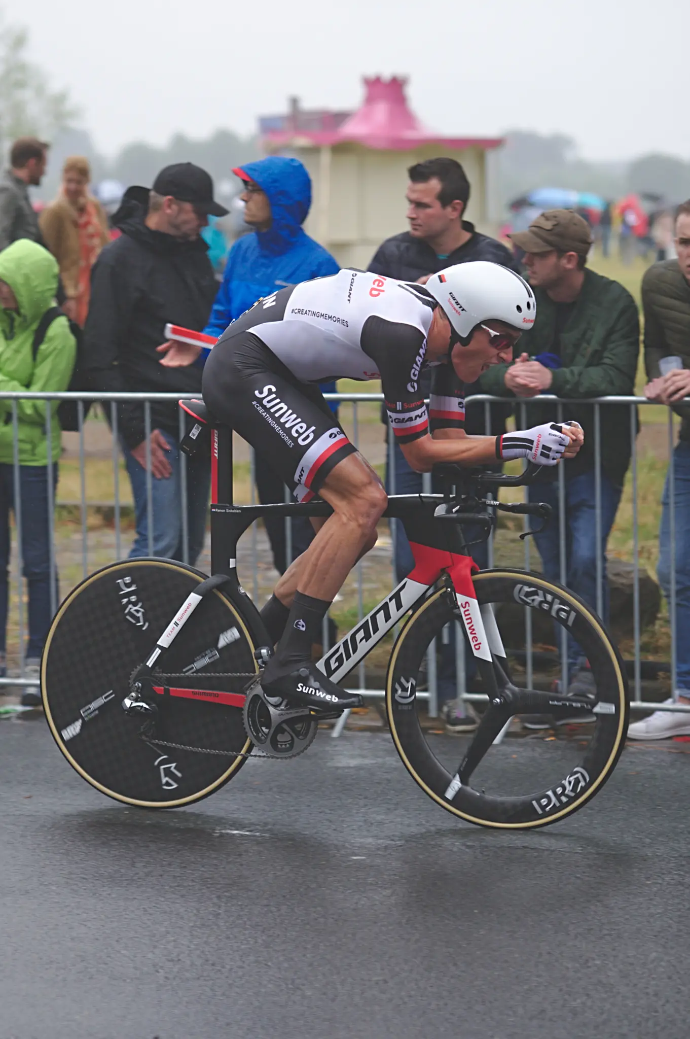 Un coureur de l'équipe Sunweb au contre-la-montre, longeant des spectateurs abrités derrière des barrières