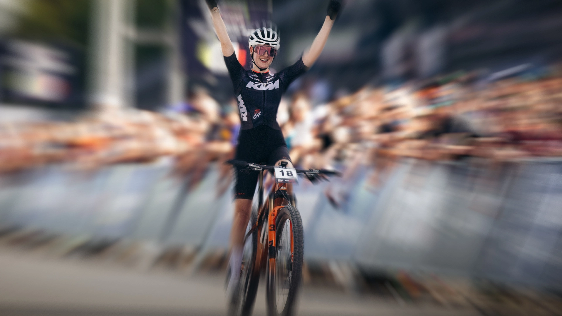 A rider from the KTM team crosses the line with arms raised at a cross-country World Cup round