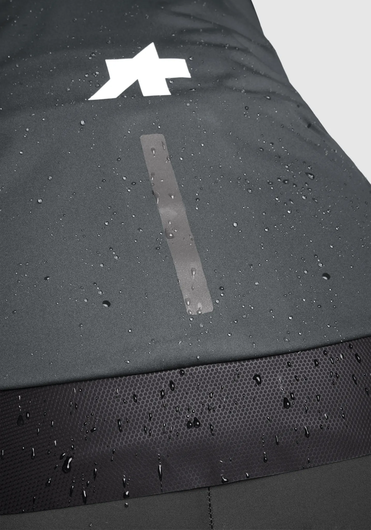 Gouttes de pluie perlant sur le dos de la veste Assos Equipe R Hydra, logo réfléchissant