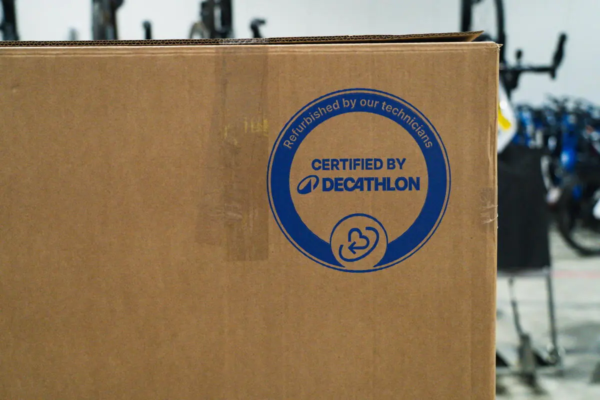 Carton portant le tampon bleu Certified by Decathlon et la mention Refurbished by our technicians