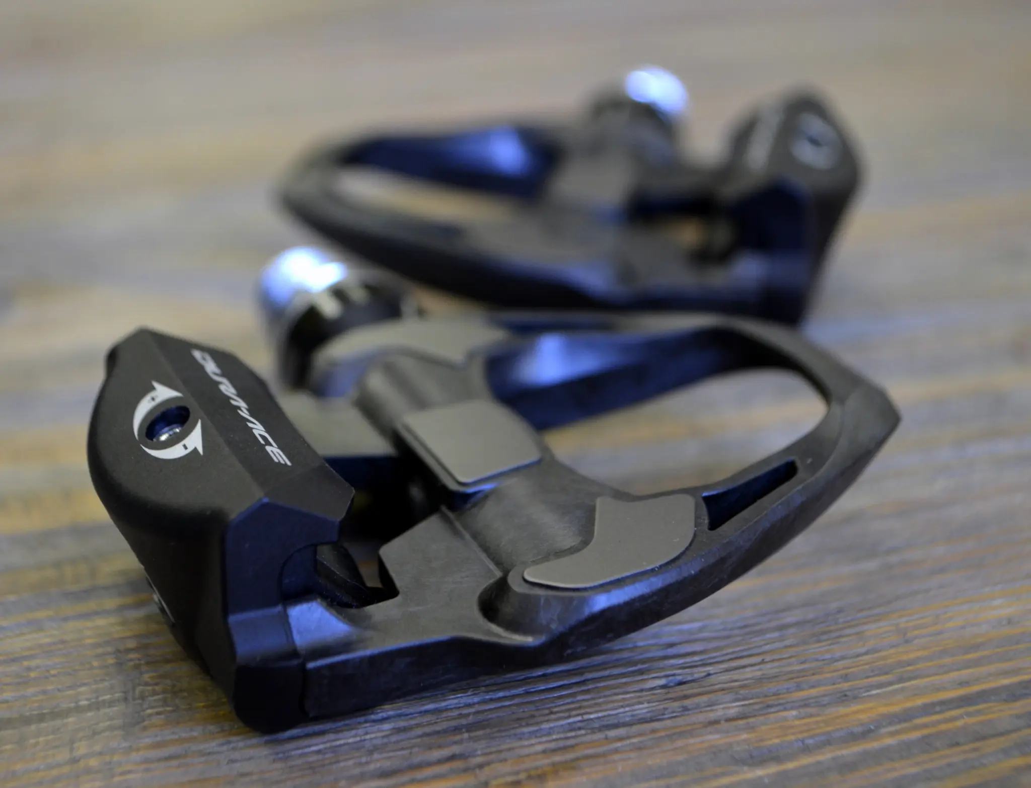 Paire de pédales route Shimano Dura-Ace PD-R9100 noires posées sur un plan de travail en bois