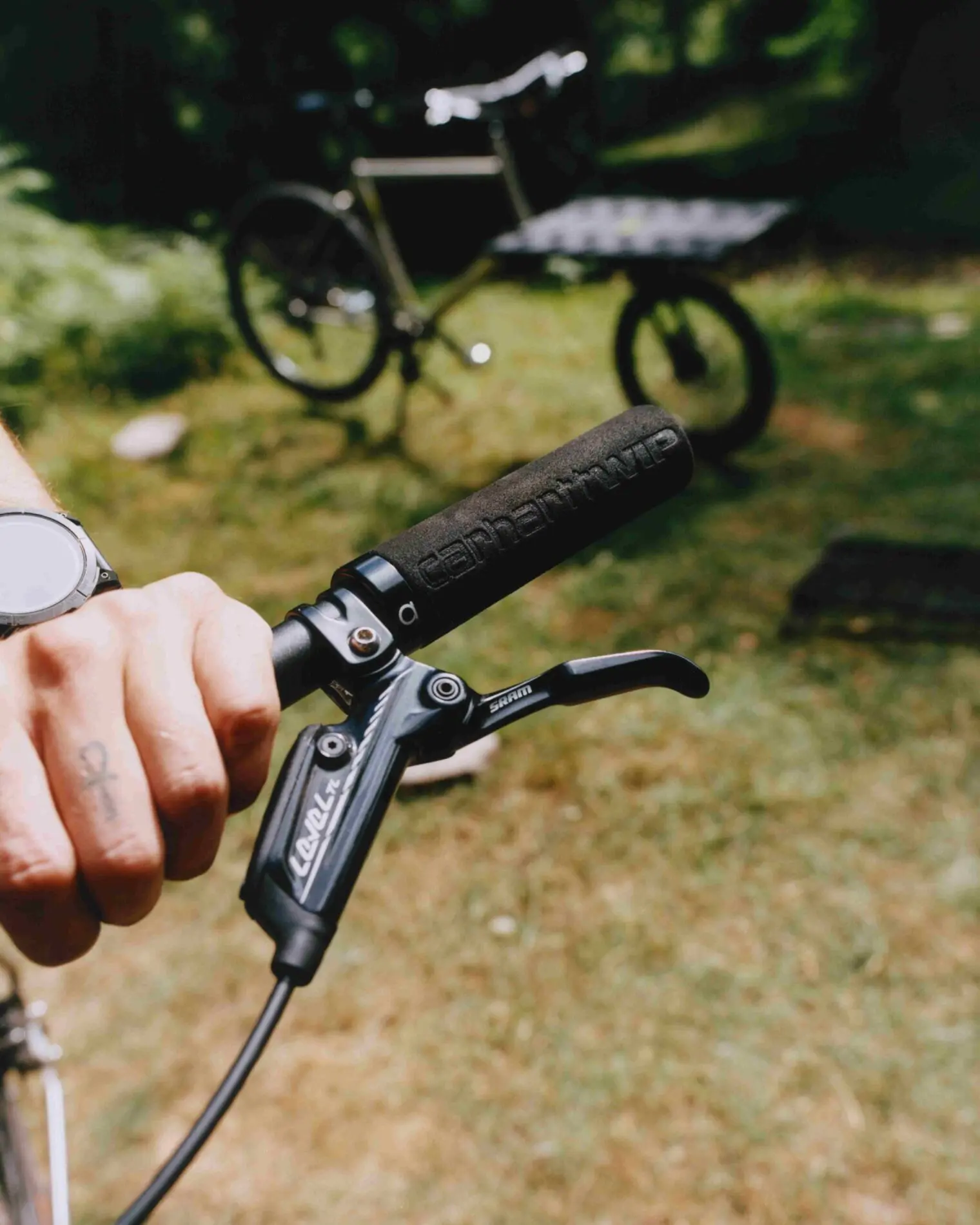 Omnium Mini-Max x Carhartt WIP: hand on the handlebar, foam grip marked Carhartt WIP and SRAM Level TL brake lever