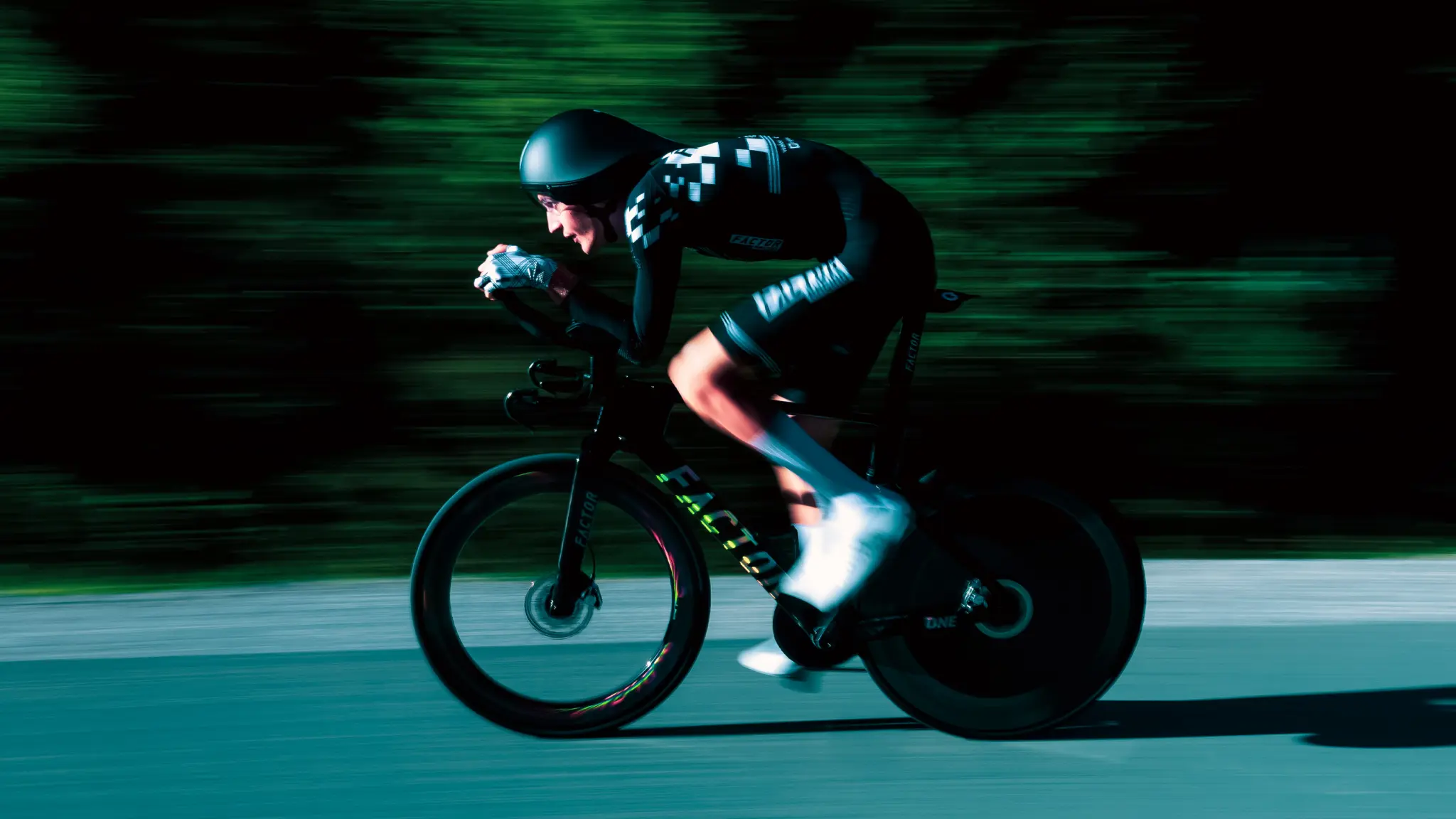 Coureur casqué en position aérodynamique sur le Factor ONE SP, fond de forêt flou