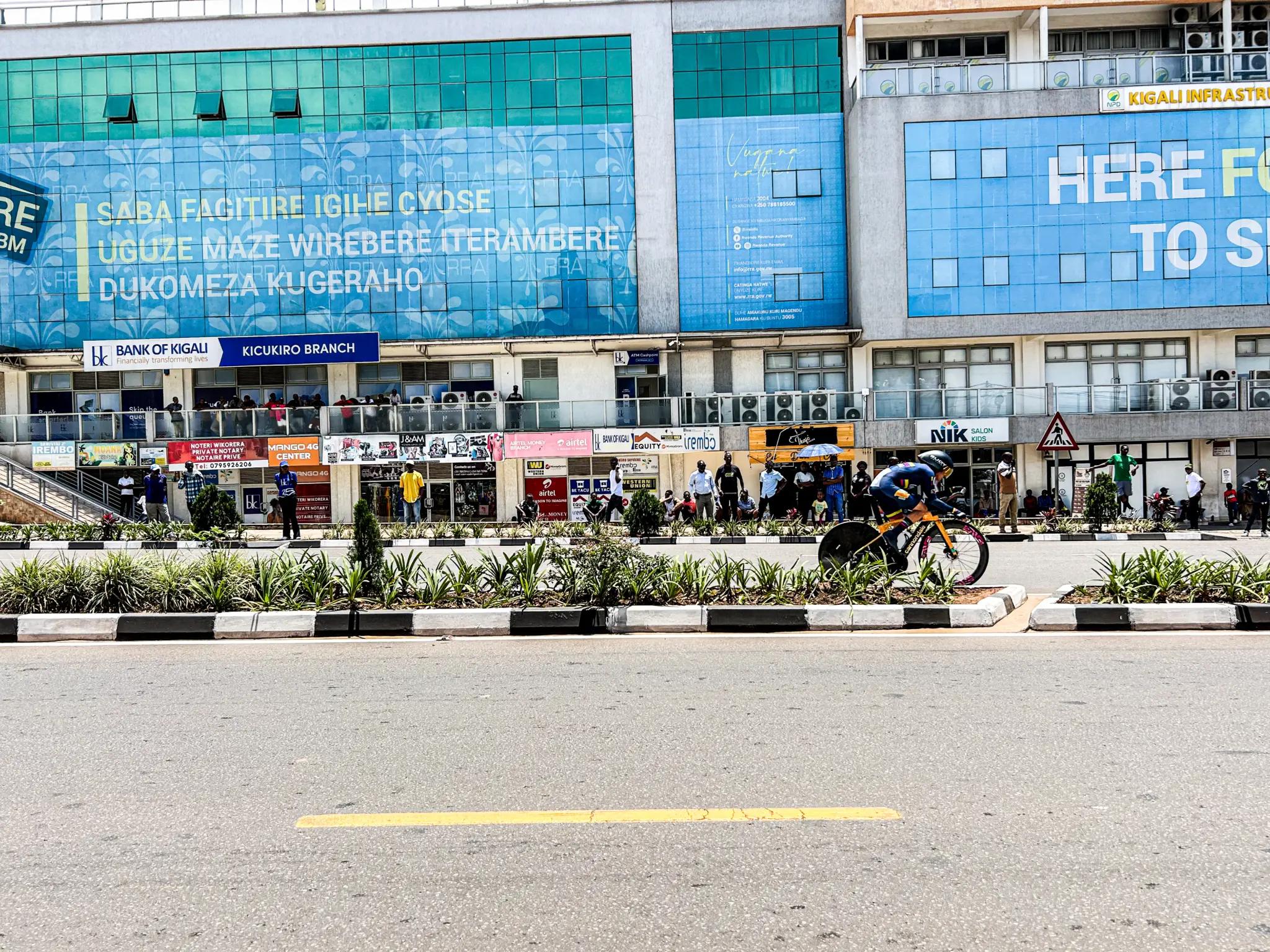 Coureur sur un vélo de contre-la-montre à roue lenticulaire devant des immeubles de Kigali, Mondiaux route UCI 2025 où les traceurs GPS équipaient toutes les catégories