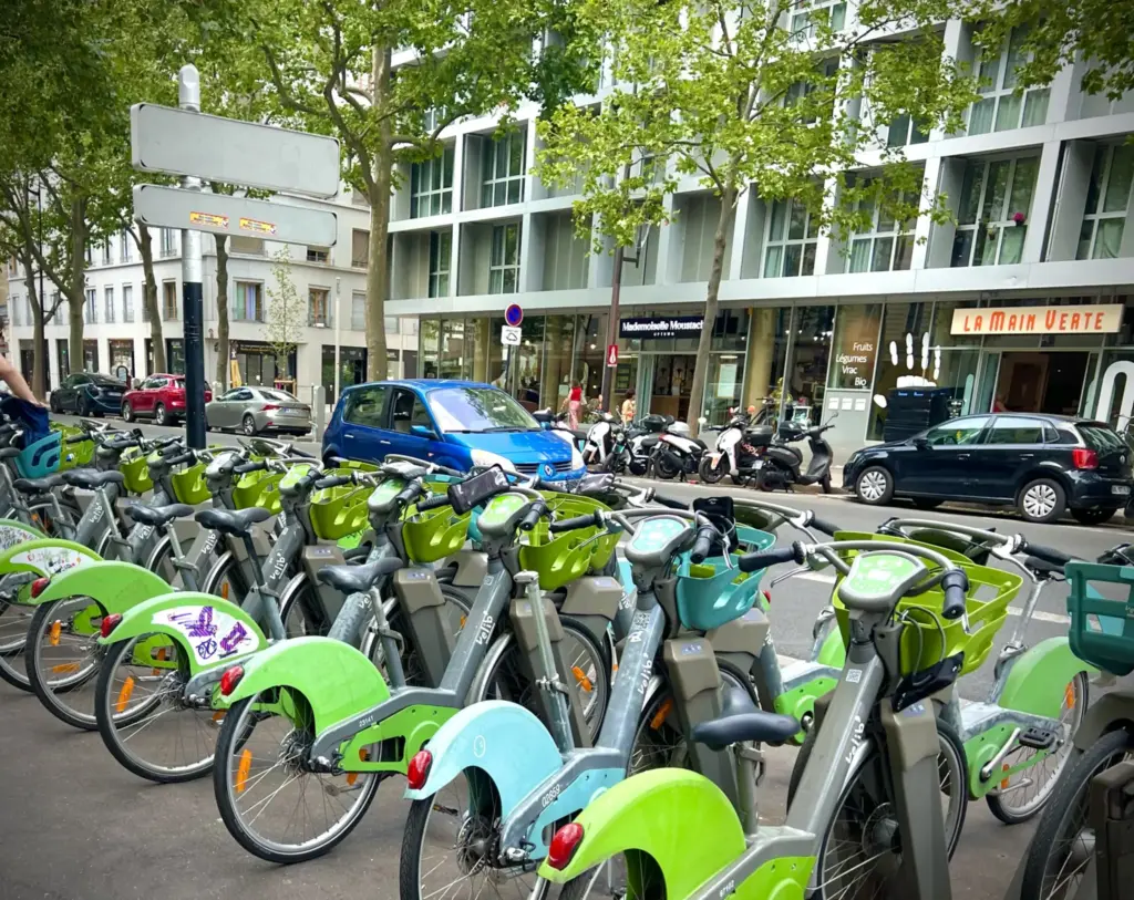 Station de vélos en libre-service à Paris, où le casque à vélo n'est pas obligatoire : des vélos verts et bleus alignés le long d'un trottoir