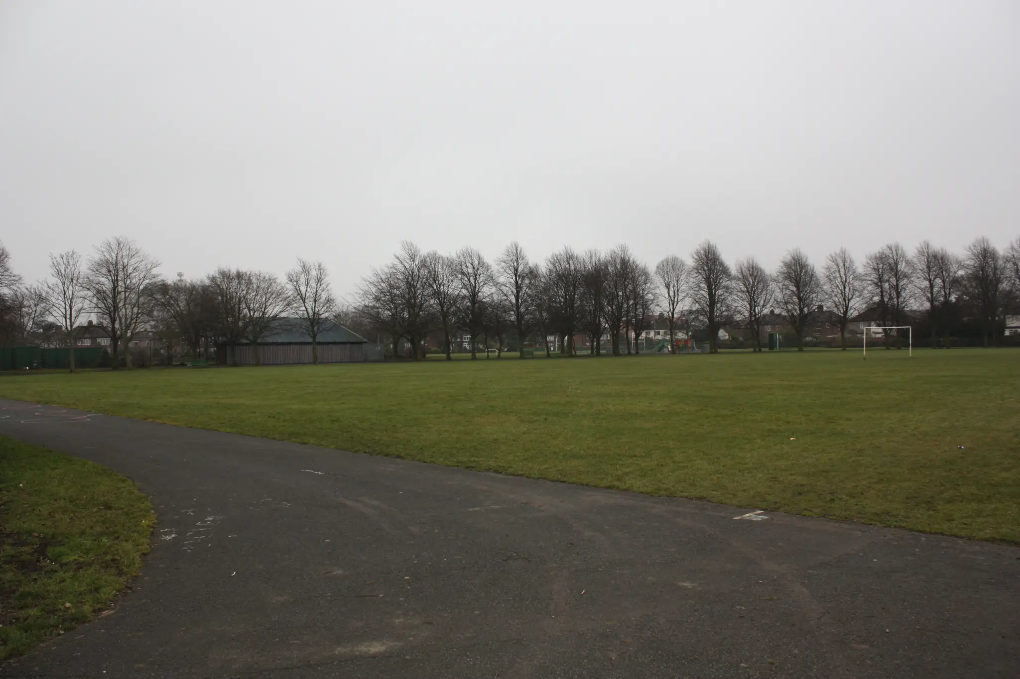 Chemin goudronné traversant une pelouse bordée d'arbres nus dans un parc de Thornaby, par temps gris