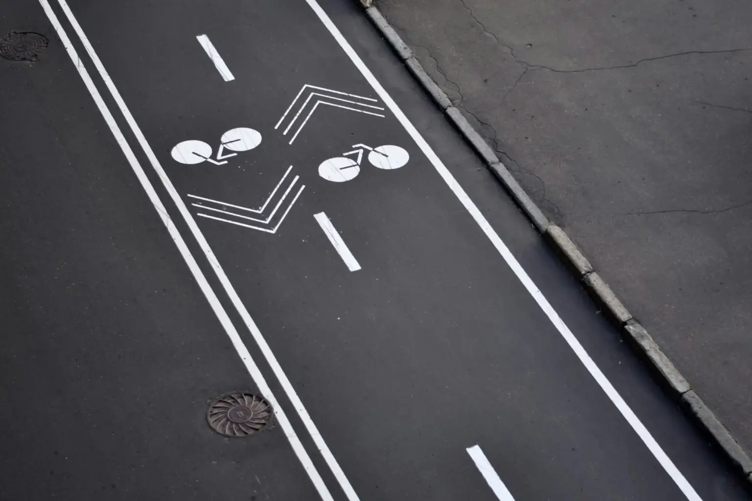 Marquage au sol d une piste cyclable fraichement peinte : deux pictogrammes de velo et des chevrons blancs sur l asphalte