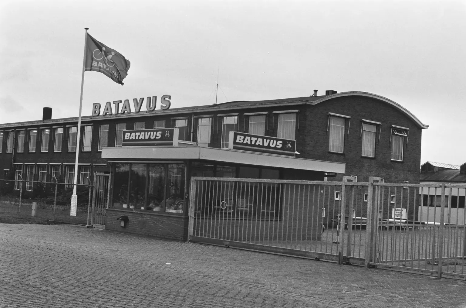 Façade de l'usine Batavus à Heerenveen, avec ses enseignes BATAVUS, un drapeau et une grille d'entrée