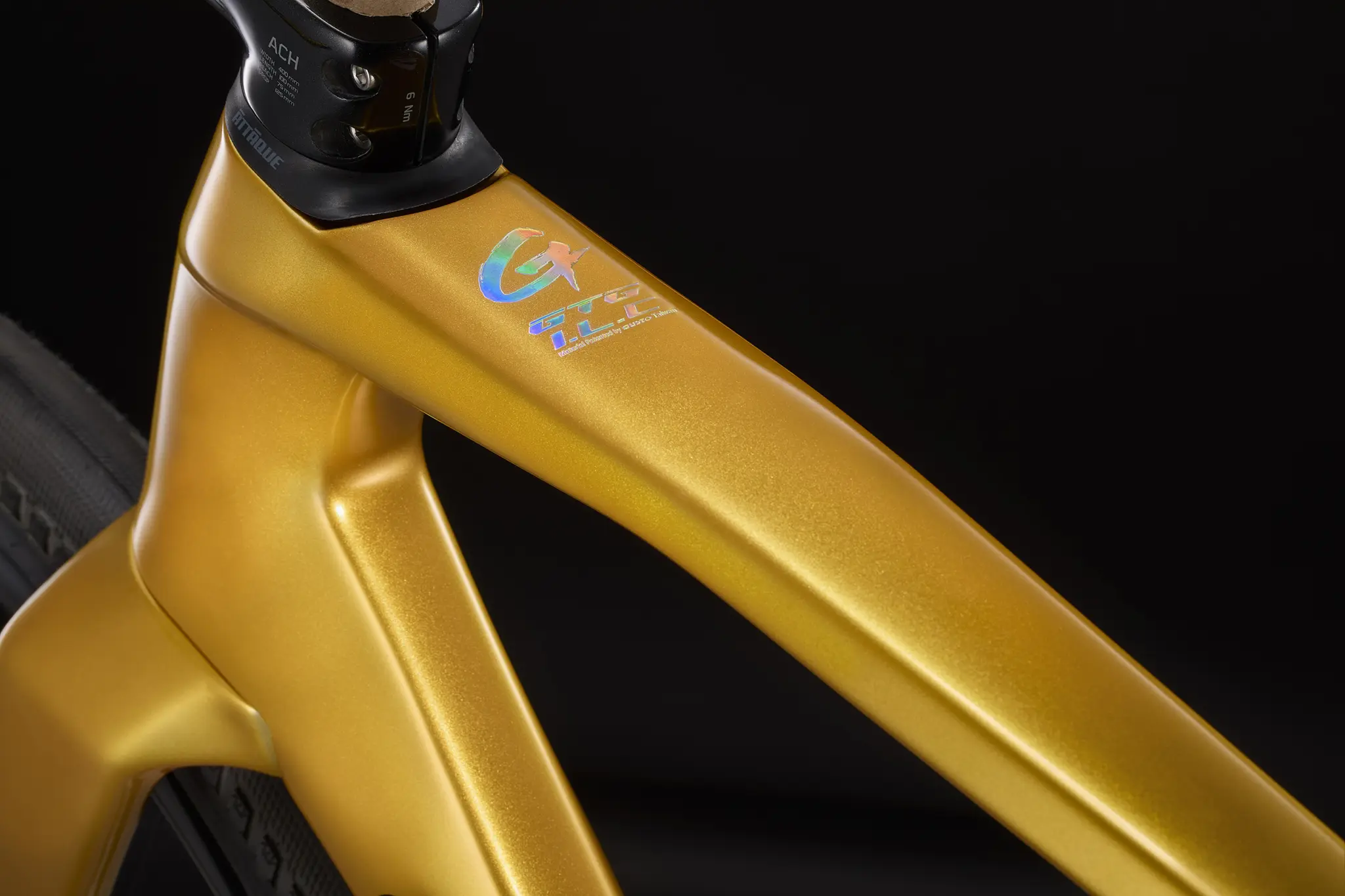 Close-up of the gold top tube of a Gusto GTG frame, with a holographic logo near the headset