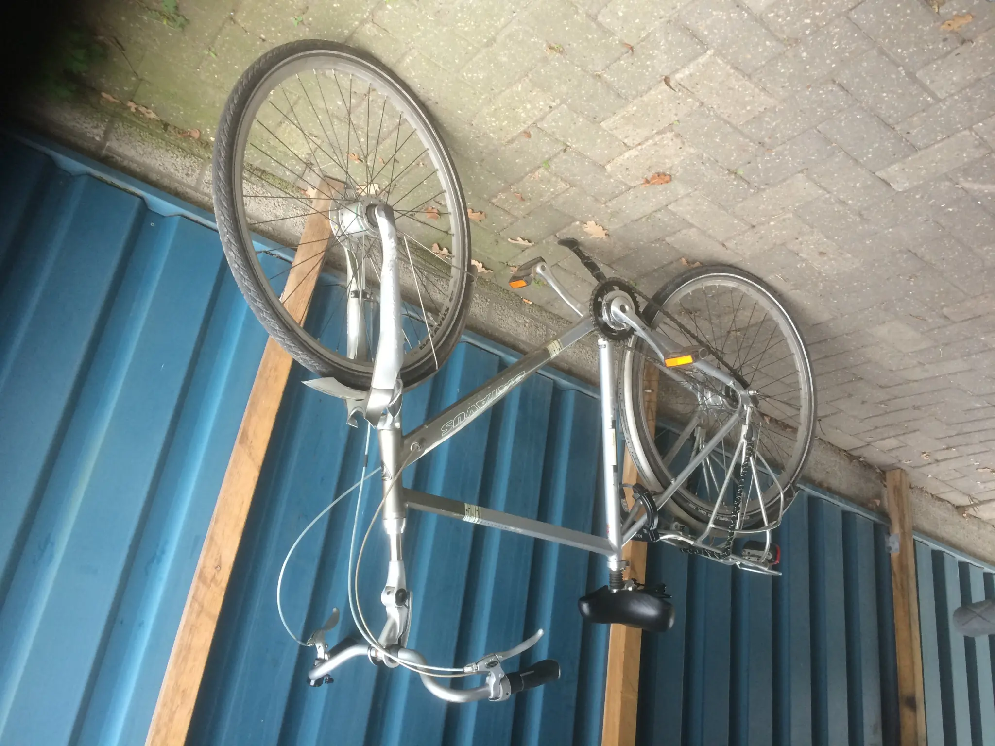Vélo de ville Batavus, marque du groupe Accell, garé contre une palissade bleue sur des pavés