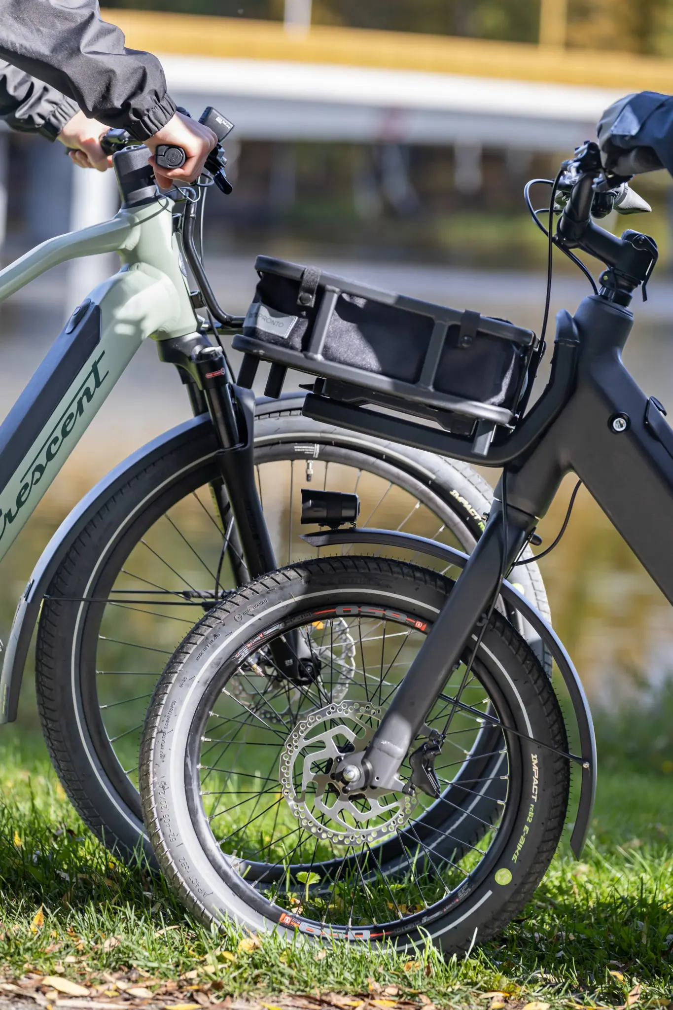 Front wheels of two e-bikes parked on grass, fitted with Suomi Tyres tyres with Impact on the sidewall