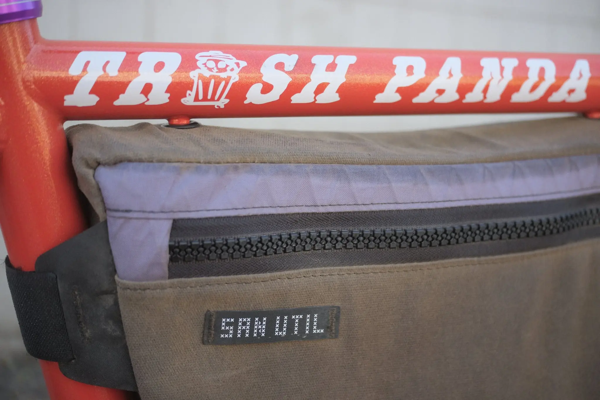 The Trash Panda name painted in white on the orange top tube, above a frame bag