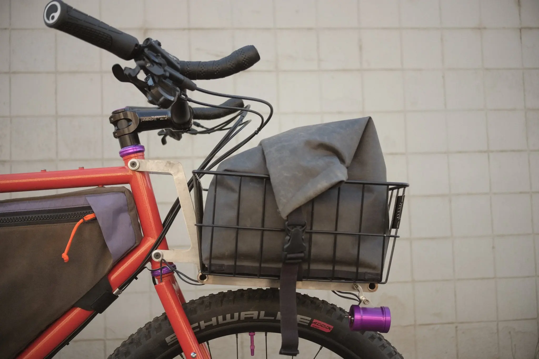 The Trash Panda ATTB's front rack, mounted to the frame below the handlebar, with a basket and a dry bag