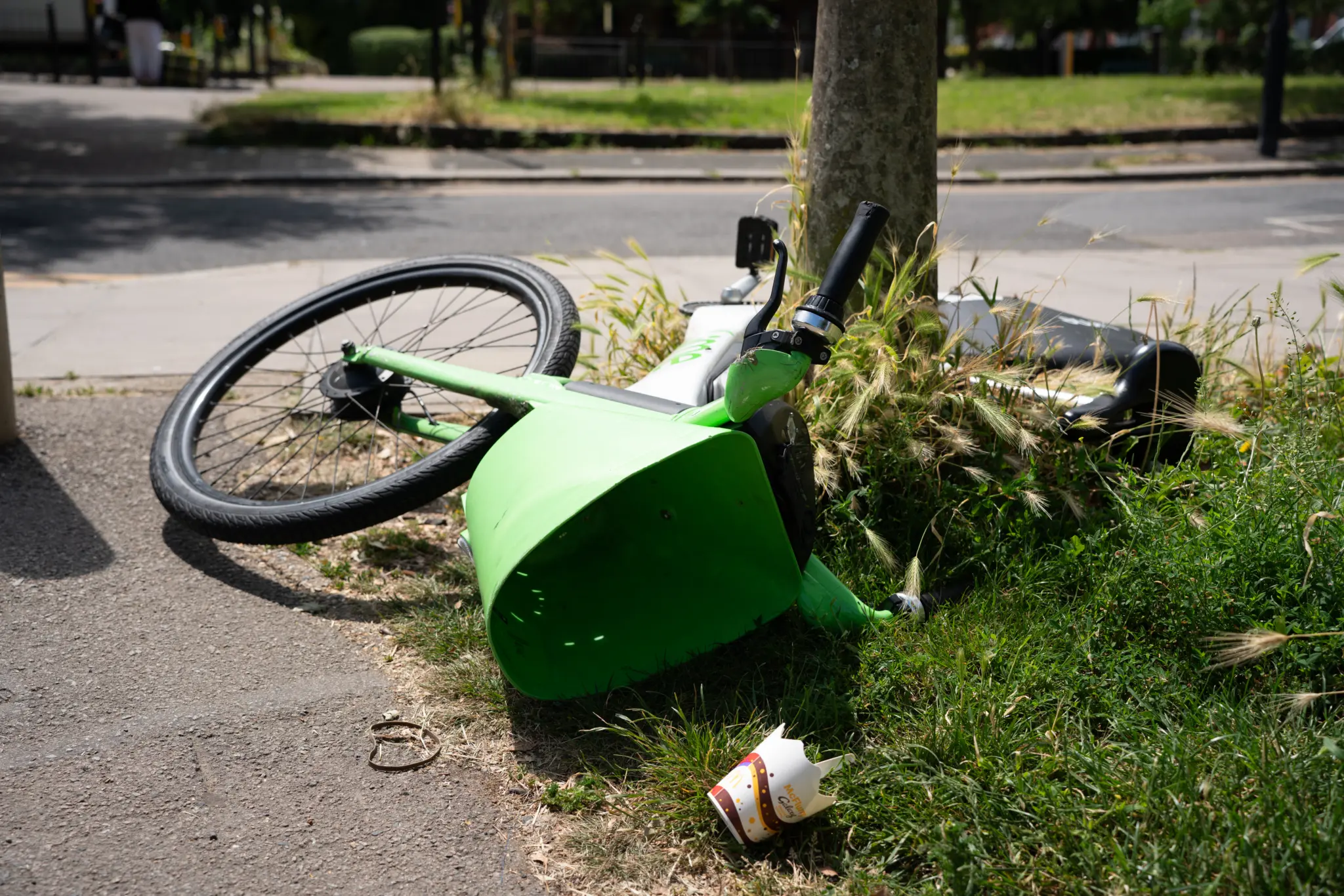 Vélo électrique Lime couché sur l'herbe au bord d'un trottoir à Wood Green, Londres