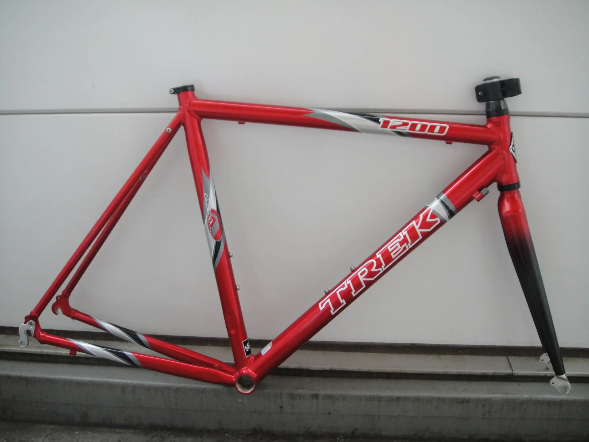 Red Trek 1200 road bike frame and fork leaning against a wall
