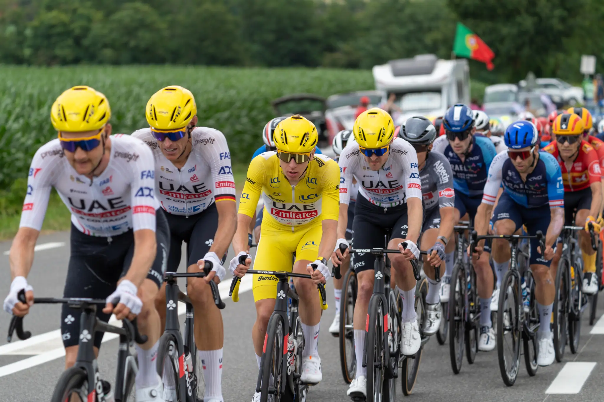 Tadej Pogačar en maillot jaune entouré de coéquipiers UAE en tête du peloton sur une route de campagne