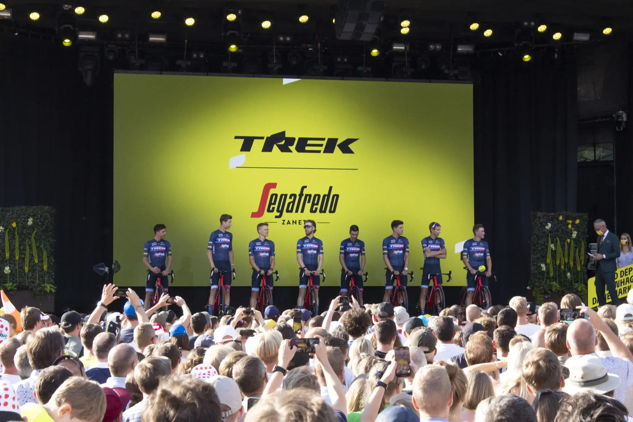 Trek-Segafredo riders lined up on stage with their bikes in front of a crowd, at the 2022 Tour de France team presentation