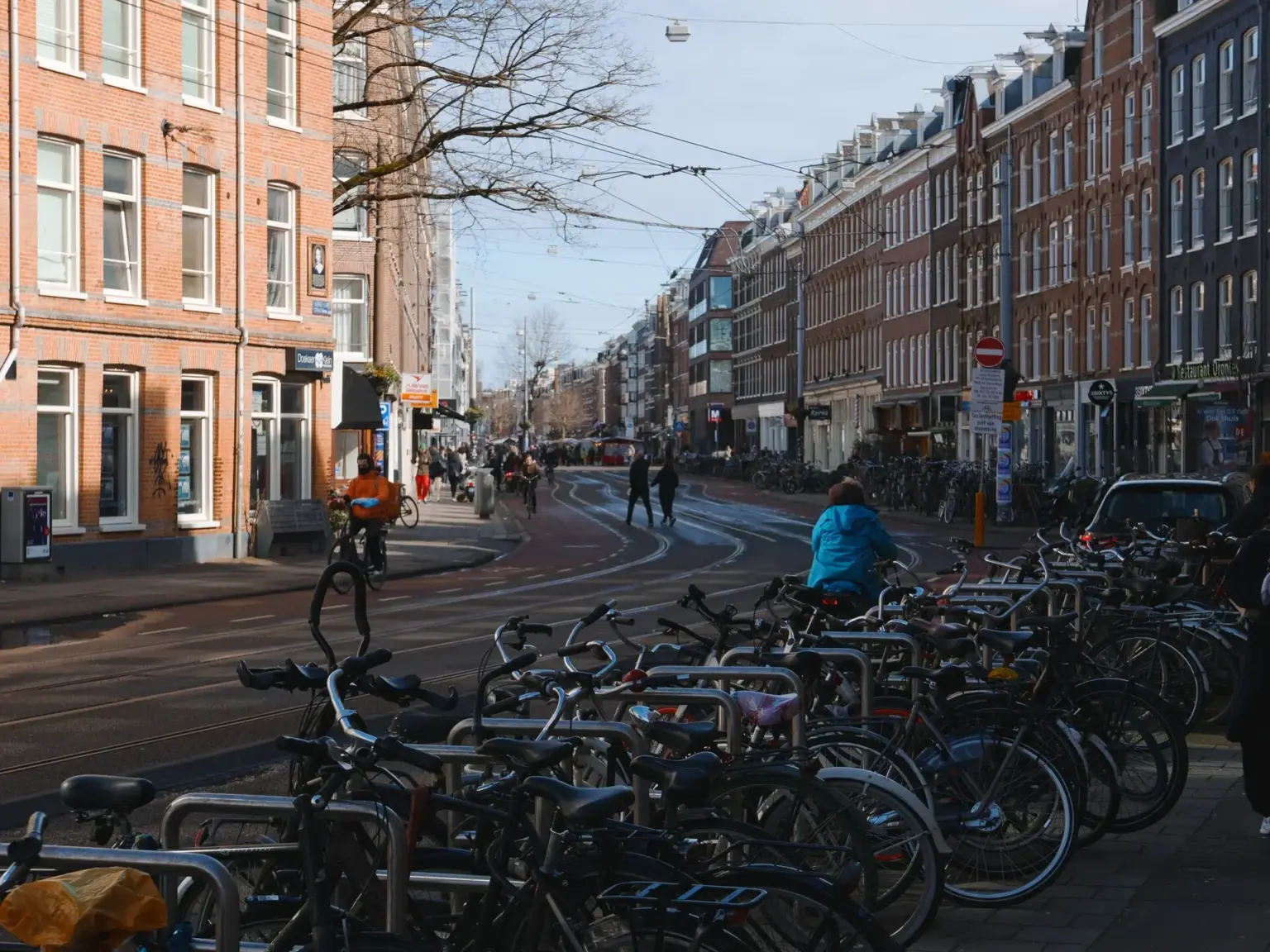 Une rue d'Amsterdam baignée de soleil, bordée de dizaines de vélos garés