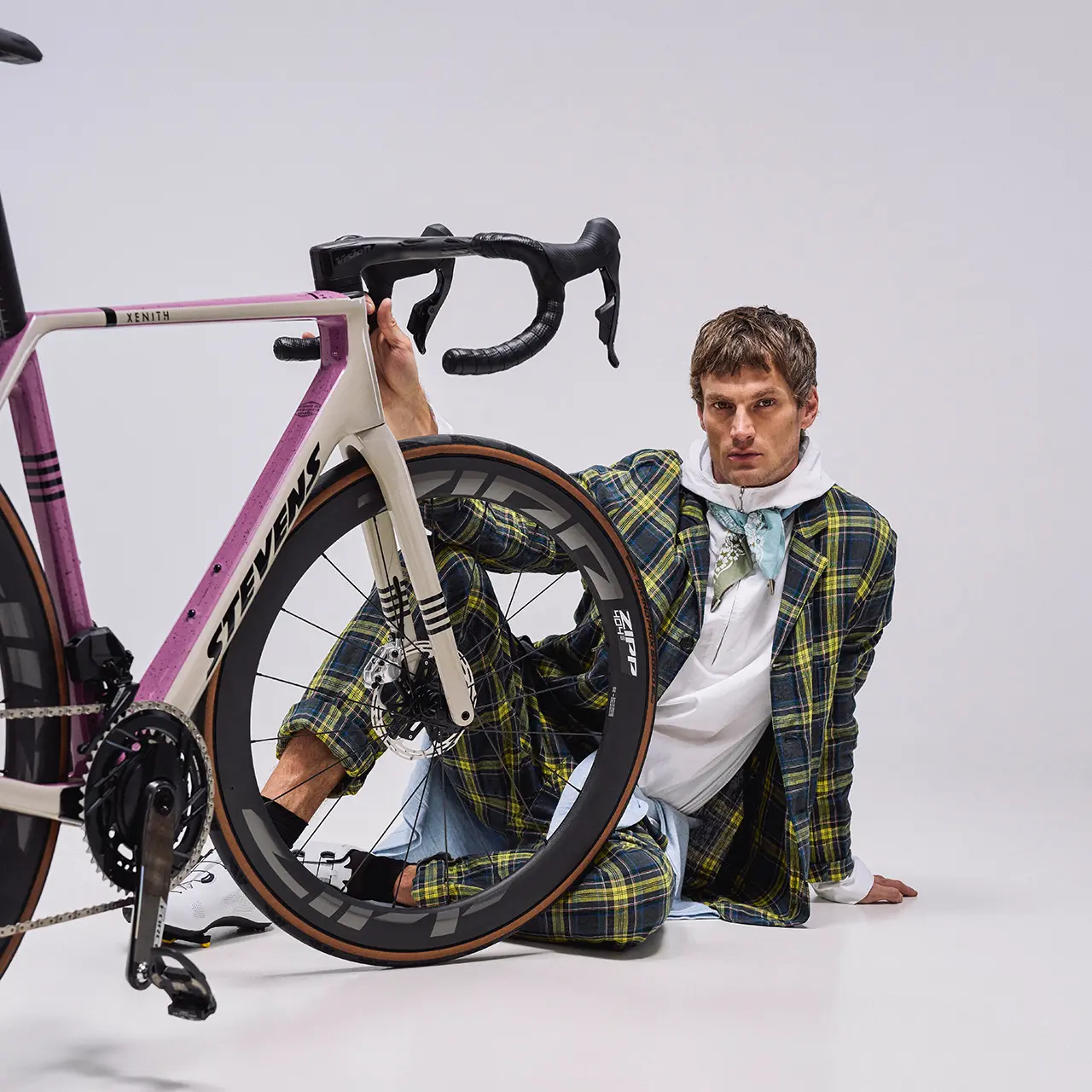 Vélo de route Stevens Xenith rose et crème, un homme assis derrière la roue avant