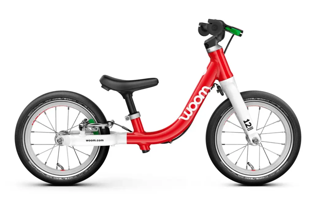 La draisienne woom GO 1 rouge, vue de profil, avec son levier de frein vert